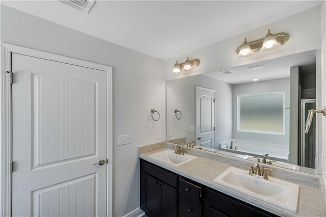 bathroom featuring a bath, a sink, visible vents, and double vanity