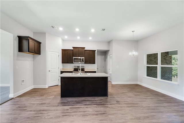 kitchen with dark brown cabinetry, sink, hanging light fixtures, appliances with stainless steel finishes, and a notable chandelier