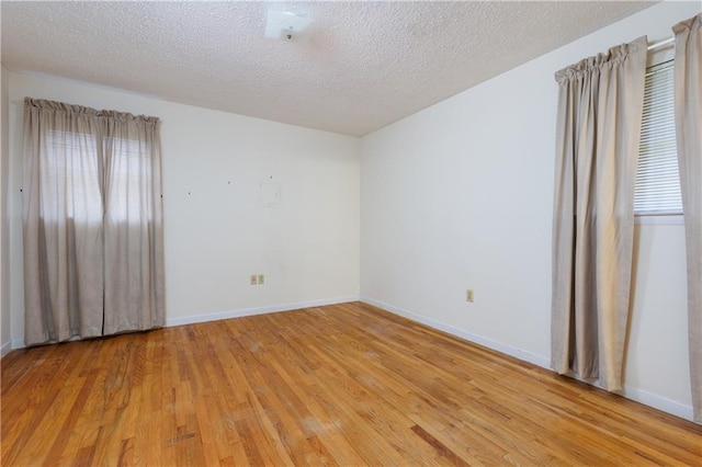 unfurnished room with a textured ceiling and light wood-type flooring