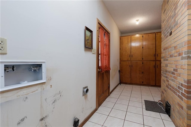 entryway with light tile patterned floors, a textured ceiling, and brick wall