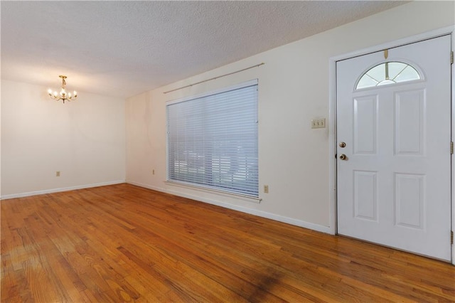 entryway with an inviting chandelier, hardwood / wood-style flooring, and a textured ceiling