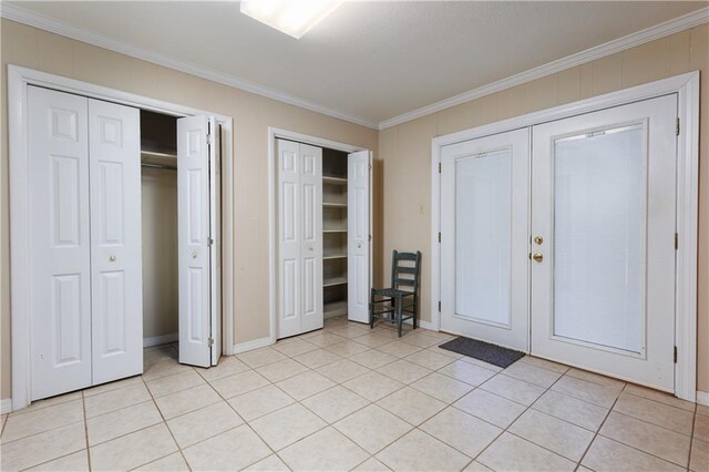 unfurnished bedroom featuring multiple closets, crown molding, and light tile patterned floors