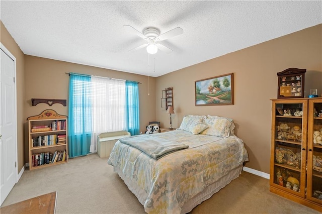 carpeted bedroom featuring ceiling fan and a textured ceiling