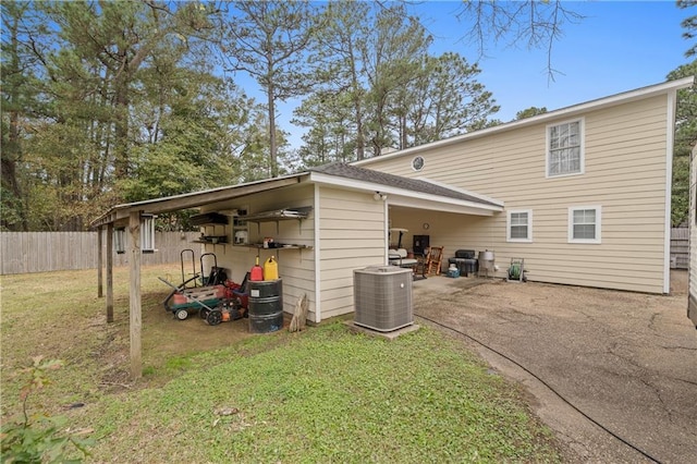 rear view of house featuring cooling unit and a yard