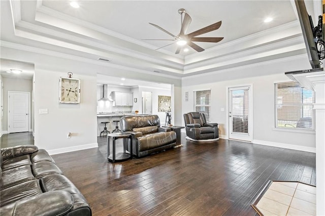 living room featuring crown molding, ceiling fan, a raised ceiling, and dark hardwood / wood-style flooring