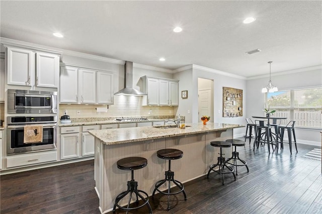 kitchen with dark hardwood / wood-style floors, decorative light fixtures, stainless steel appliances, and wall chimney range hood