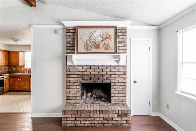 unfurnished living room with a textured ceiling, light wood finished floors, baseboards, ornamental molding, and a brick fireplace