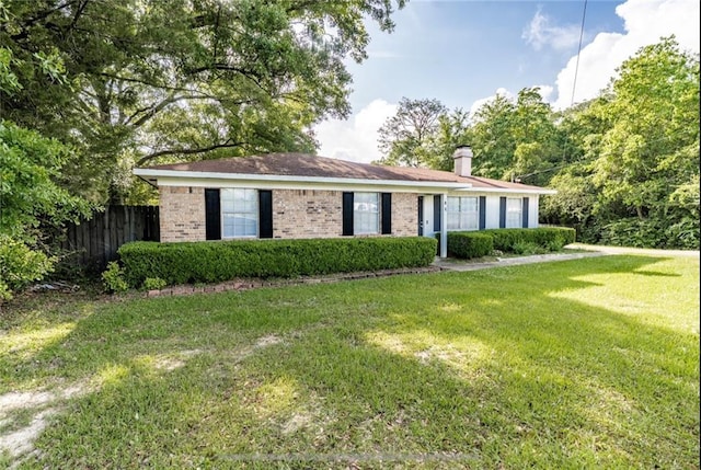 view of front facade with a chimney, a front lawn, brick siding, and fence