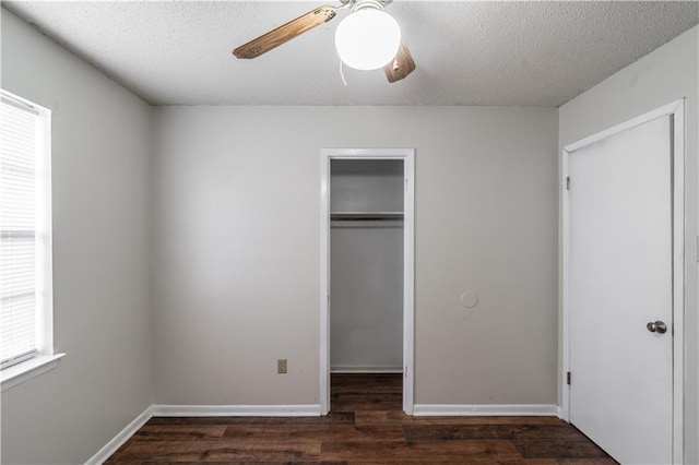 unfurnished bedroom featuring a spacious closet, wood finished floors, a ceiling fan, a closet, and a textured ceiling
