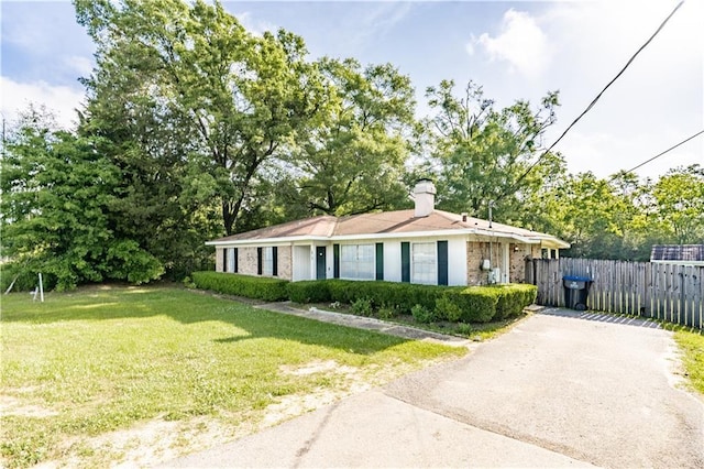 ranch-style house with a front lawn, fence, and driveway