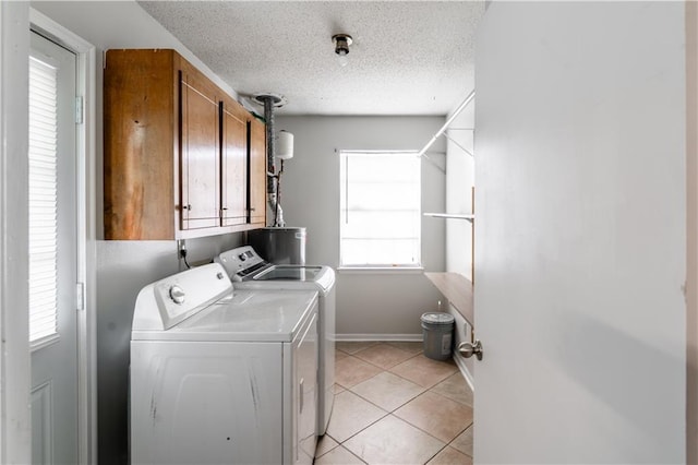 laundry room featuring washer and dryer, light tile patterned floors, cabinet space, and a healthy amount of sunlight