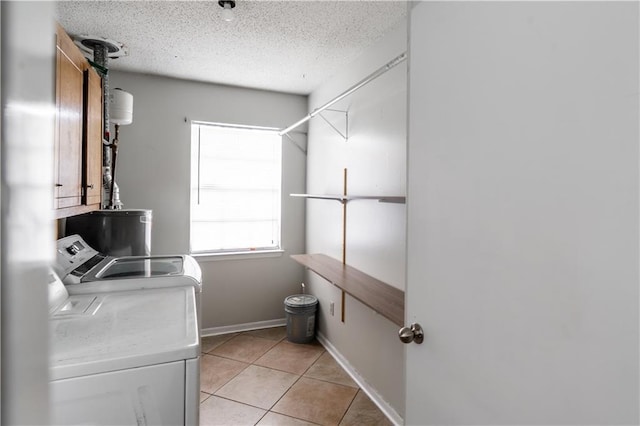 laundry area featuring laundry area, light tile patterned floors, washing machine and dryer, baseboards, and a textured ceiling