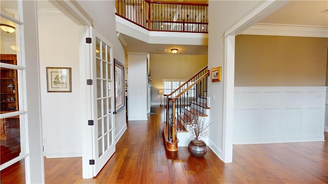 entrance foyer featuring wood-type flooring, ornamental molding, french doors, and a high ceiling