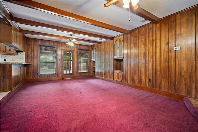 504 Vaughan Dr N, Satsuma, AL 36572 - unfurnished living room with ceiling fan, beam ceiling, wood walls, and carpet flooring