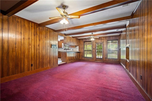 504 Vaughan Dr N, Satsuma, AL 36572 - unfurnished living room featuring beam ceiling, a ceiling fan, wooden walls, and carpet