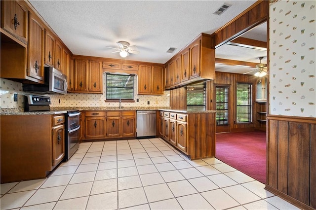 504 Vaughan Dr N, Satsuma, AL 36572 - kitchen featuring appliances with stainless steel finishes, ceiling fan, plenty of natural light, a textured ceiling, and wood walls
