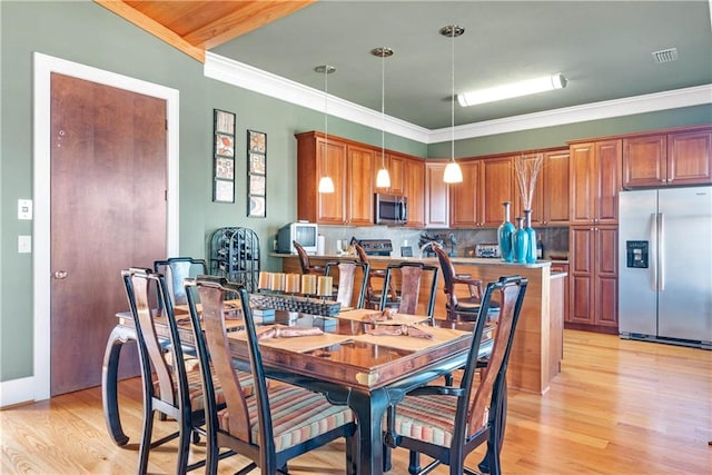 dining room featuring light wood-type flooring and crown molding