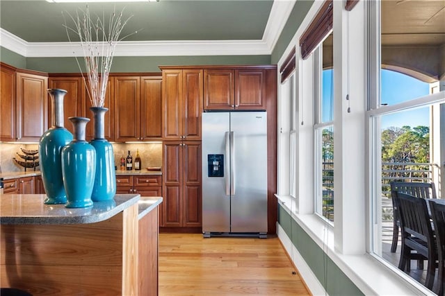 kitchen featuring tasteful backsplash, stone counters, light hardwood / wood-style flooring, crown molding, and stainless steel fridge