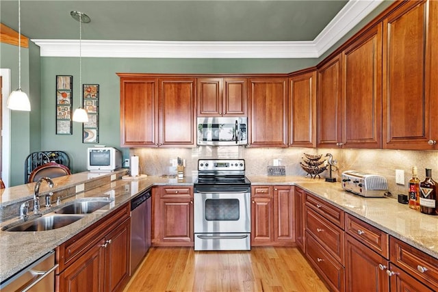 kitchen featuring sink, hanging light fixtures, light hardwood / wood-style flooring, stainless steel appliances, and crown molding