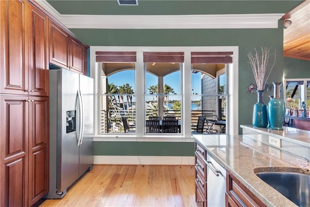 kitchen with light stone countertops, appliances with stainless steel finishes, crown molding, and light hardwood / wood-style flooring