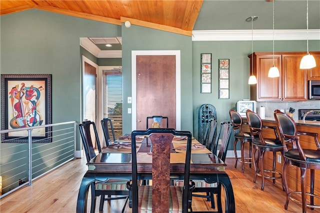 dining room with ornamental molding, wood ceiling, vaulted ceiling, and light hardwood / wood-style flooring