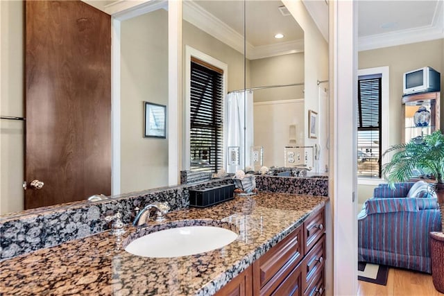 bathroom featuring ornamental molding, vanity, hardwood / wood-style floors, and a wealth of natural light