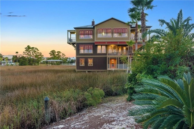 back house at dusk featuring a balcony