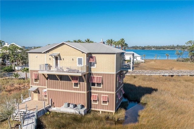 back of property with a water view and a balcony