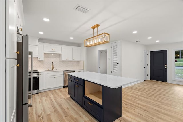 kitchen featuring a center island, visible vents, hanging light fixtures, appliances with stainless steel finishes, and white cabinetry