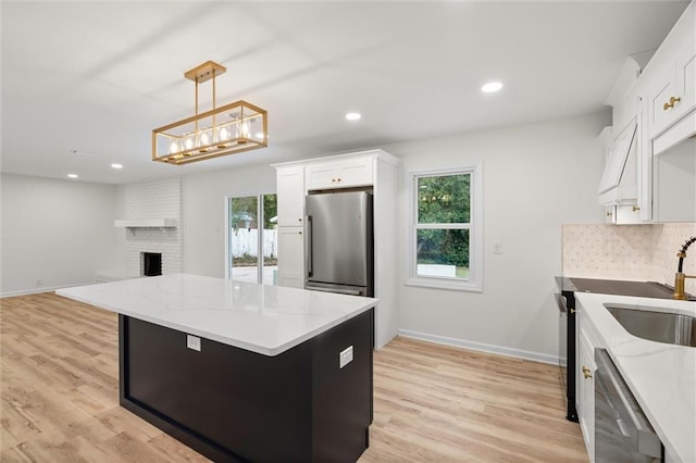 kitchen featuring decorative light fixtures, appliances with stainless steel finishes, open floor plan, white cabinets, and a kitchen island