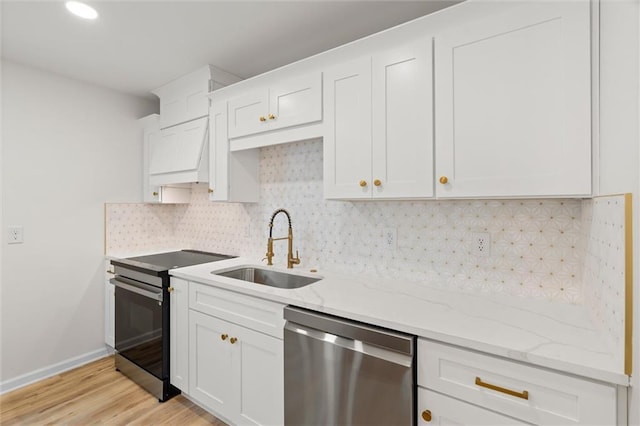 kitchen with light stone countertops, white cabinetry, stainless steel appliances, and a sink