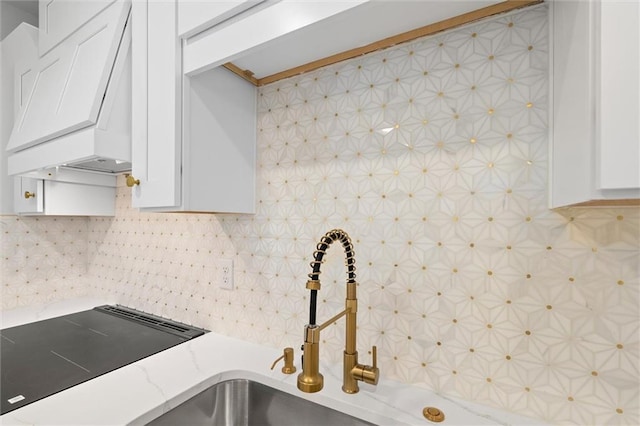 kitchen with premium range hood, white cabinetry, light countertops, and backsplash