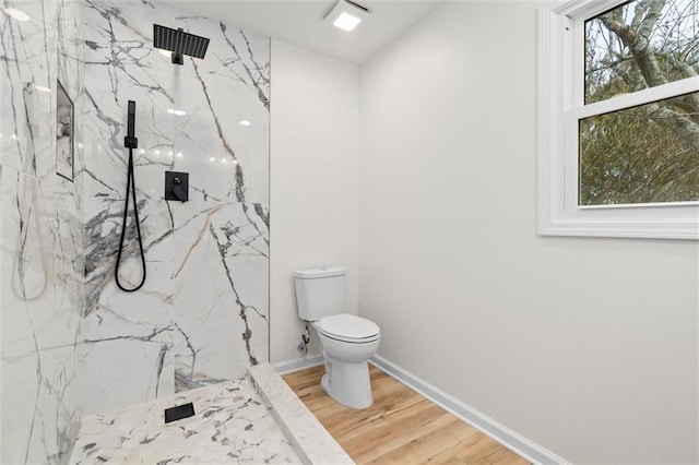 full bathroom with toilet, a marble finish shower, baseboards, and wood finished floors