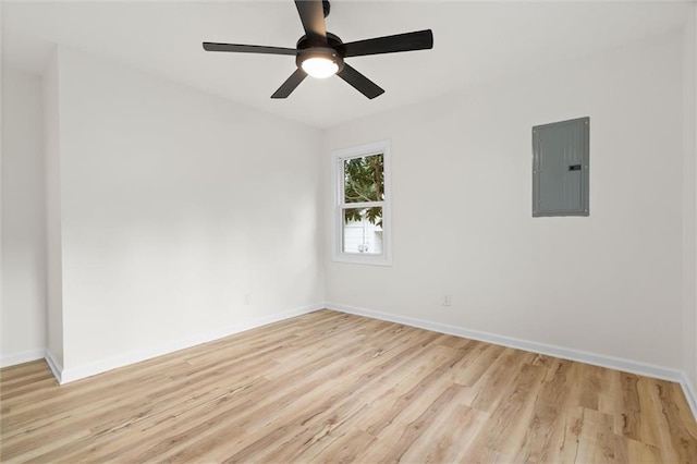 spare room featuring baseboards, electric panel, and light wood finished floors