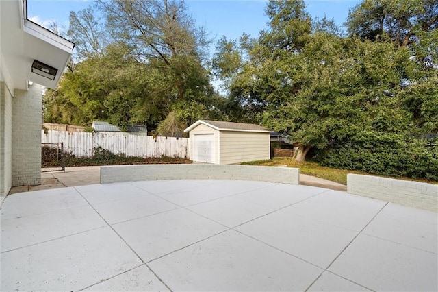 view of patio / terrace featuring a garage, a storage unit, fence, and an outdoor structure