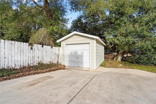 detached garage with concrete driveway and fence