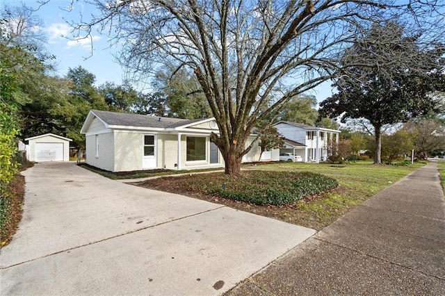 view of front of house with stucco siding, concrete driveway, a garage, an outdoor structure, and a front lawn