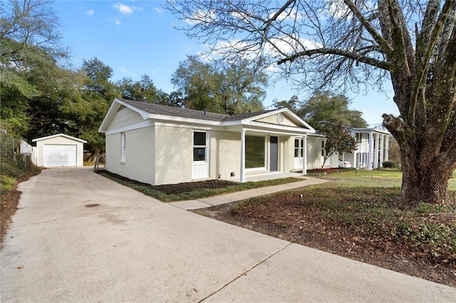 view of front of house featuring driveway, brick siding, a detached garage, and an outdoor structure