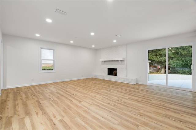 unfurnished living room featuring recessed lighting, visible vents, light wood-style flooring, a brick fireplace, and baseboards