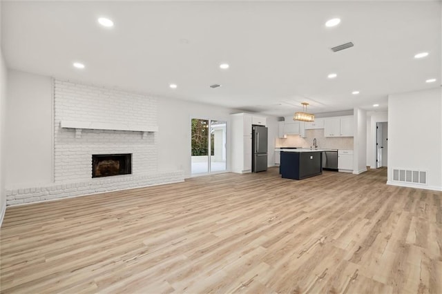 unfurnished living room featuring light wood-type flooring, visible vents, a fireplace, and recessed lighting