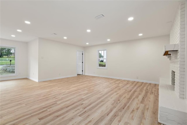 unfurnished living room with a brick fireplace, light wood-style flooring, and recessed lighting