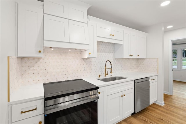 kitchen with stainless steel appliances, a sink, light wood-style floors, white cabinets, and light countertops