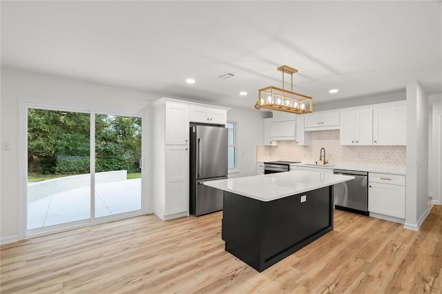 kitchen with pendant lighting, stainless steel appliances, light countertops, white cabinets, and a kitchen island