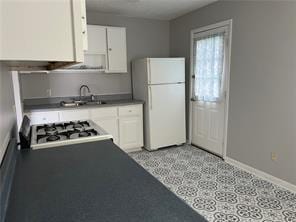 kitchen with white cabinets, white refrigerator, and sink