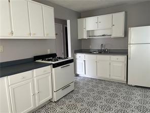 kitchen featuring white cabinetry, sink, and white appliances