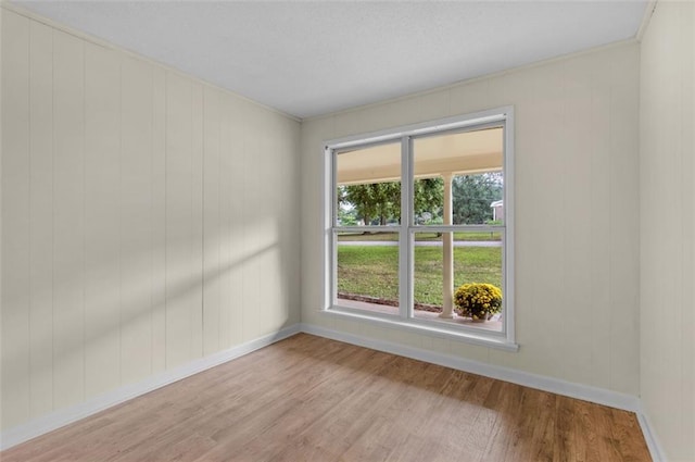 unfurnished room with light hardwood / wood-style floors and wood walls