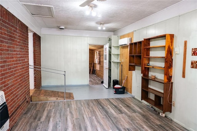 interior space with wood finished floors, heating unit, a textured ceiling, and brick wall