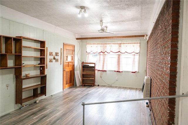 spare room featuring wood finished floors, ceiling fan, baseboards, and a textured ceiling