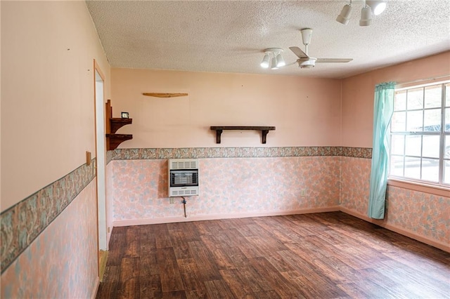 unfurnished room featuring wood finished floors, heating unit, a textured ceiling, and wainscoting