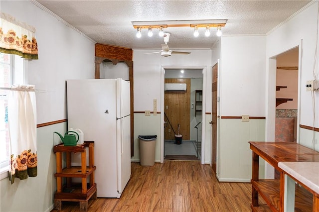 hall with wainscoting, a wall unit AC, a textured ceiling, and wood finished floors